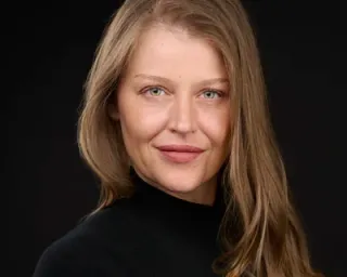 Professional influencer with warm smile in black turtleneck against dark backdrop